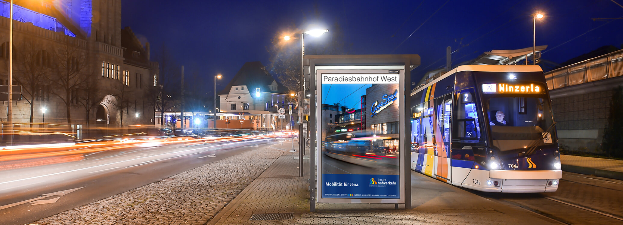 Straßenbahn an einer Haltestelle mit einem Imageplakat für den Jenaer Nahverkehr